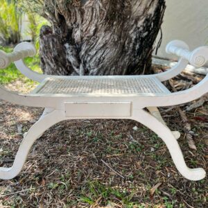 Vintage French Regency Neoclassical Style Cane Seat Curule X-Frame Stool 403d8aab-5591-53a1-b8a6-36373db04bd5-1.jpg This is a beautiful 1960s Curule Style X-frame bench in the Neoclassical style with a cane seat. This unique bench features a cream distressed painted finish, cane seat, shapely scrolling form, solid wood frame, and great style and form, circa 1960. Vintage,french regency